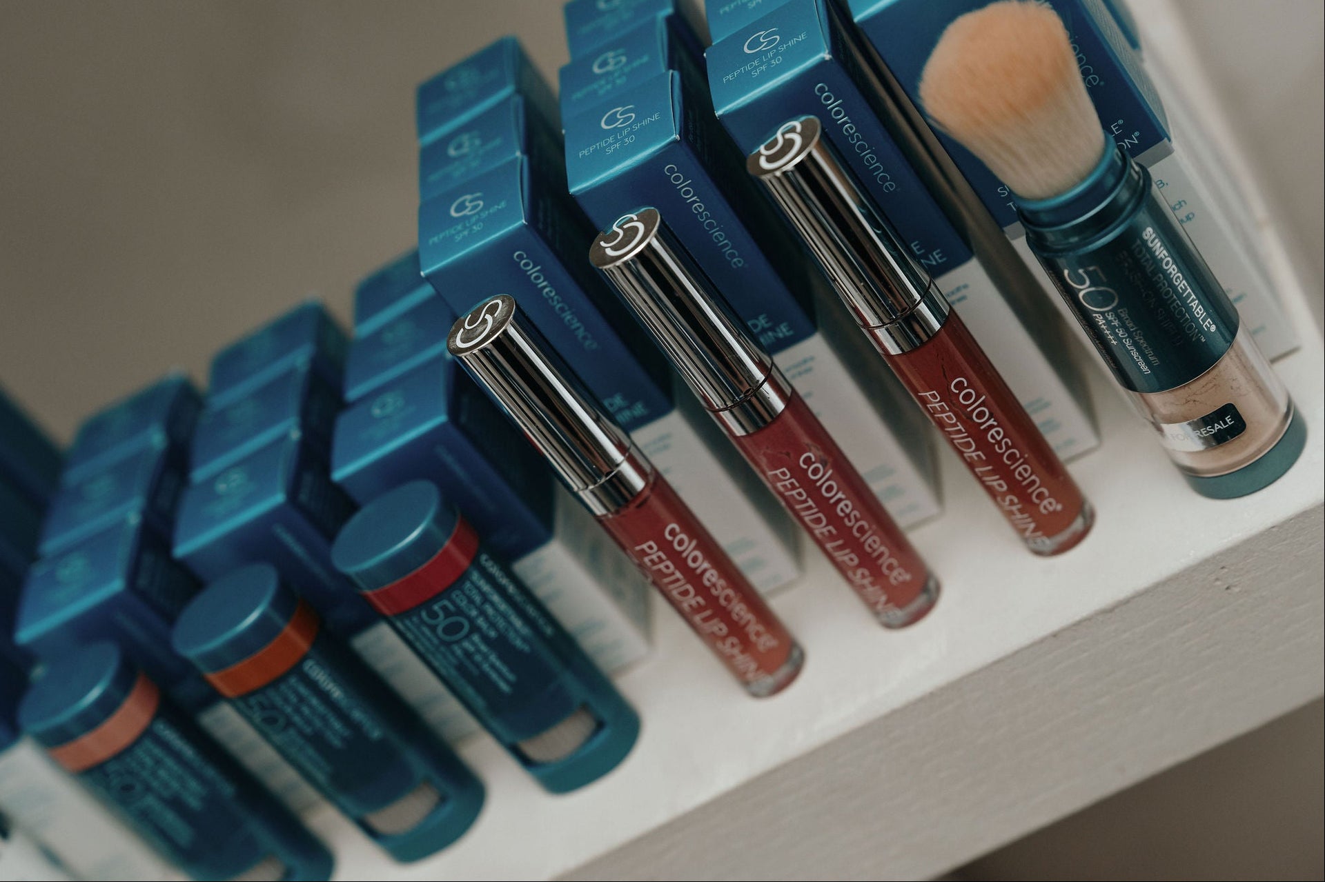 Set of makeup brushes with blue handles and various bristle colors on a white tray.